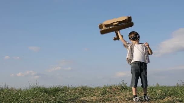 昼間は公園で段ボールのおもちゃの飛行機で遊んでいる男の子 幸せなゲームの概念 子供は屋外で楽しんでいます 青空を背景に作られた写真 — ストック動画