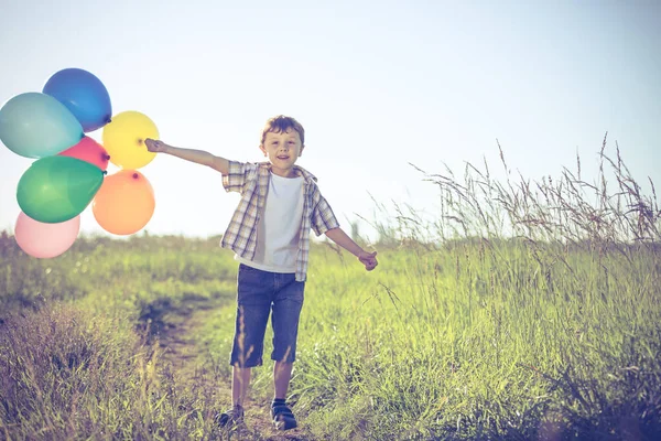 快乐的小男孩在路上玩的时候 他在田里跑着 手里拿着气球 孩子在玩大自然的把戏幸福的概念 — 图库照片