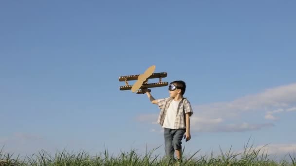 昼間は公園で段ボールのおもちゃの飛行機で遊んでいる男の子 幸せなゲームの概念 子供は屋外で楽しんでいます 青空を背景に作られた写真 — ストック動画