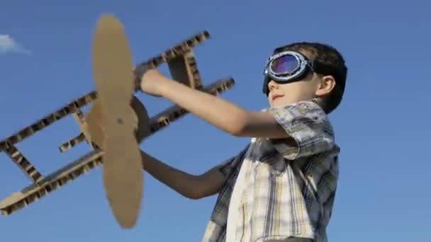 小男孩白天在公园里玩纸板玩具飞机 快乐游戏的概念 孩子们在外面玩得很开心在蓝天的背景上拍摄的图片 — 图库视频影像