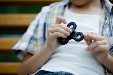 Mutlu küçük çocuk gündüz vakti parkta oynuyor. Spinner 'la oynuyor. Çocuk doğada eğleniyor. Mutluluk kavramı.