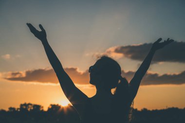 Gün batımında tarlada bir kadının silüeti. Mutluluk kavramı.