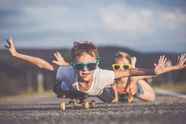 兄と妹の道路では その日の時間で演奏 子供たちは屋外で楽しんでいます 彼らは道路でスケートをしている 友好的な家族の概念 — ストック写真
