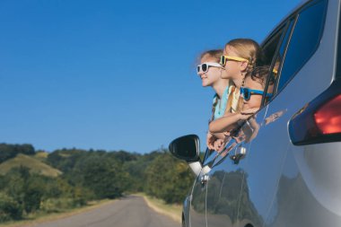 Mutlu erkek ve iki kız kardeşi gündüz vakti arabada oturuyorlar. Pencereden dışarı bakıyorlar. Çocuklar dışarıda eğleniyor. Aile kavramı seyahate hazır..