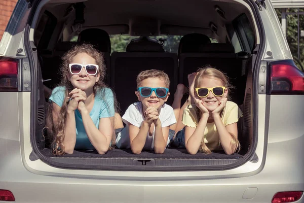 幸せな弟と彼の2人の姉妹は 車の中でその日の時間に座っている 子供たちは屋外で楽しんでいます 家族の概念は旅行の準備ができています — ストック写真