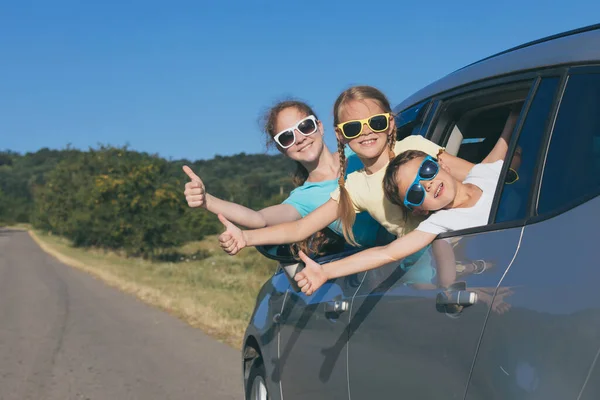 幸せな弟と彼の2人の姉妹は 車の中でその日の時間に座っている 窓の外を見てる 子供たちは屋外で楽しんでいます 家族の概念は旅行の準備ができています — ストック写真