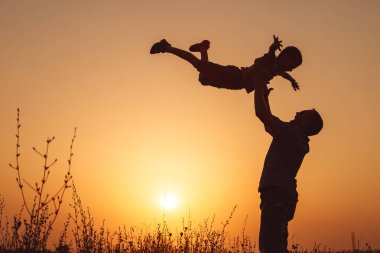 Baba ve oğul günbatımı anda parkta oynamak. İnsanlar sahada eğleniyor. Kavram dostu aile ve yaz tatili.