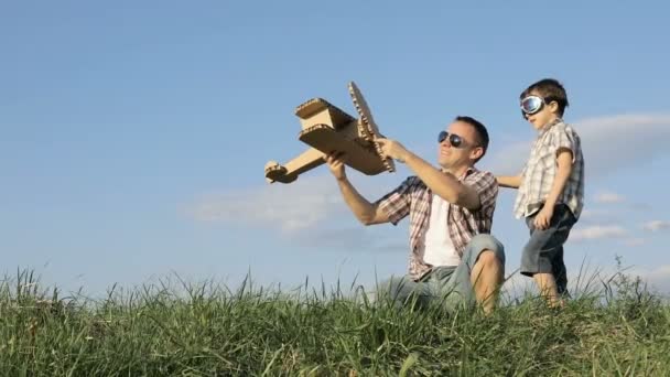 爸爸和儿子白天在公园里玩纸板玩具飞机 友好家庭的概念 人们在户外玩得很开心在蓝天的背景上拍摄的图片 — 图库视频影像