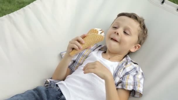 Niño Pequeño Acostado Hamaca Parque Durante Día Está Comiendo Helado — Vídeos de Stock