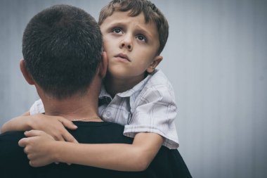 Gündüz vakti dışarıda duran üzgün küçük çocuk ve baba portresi. Üzüntü kavramı.