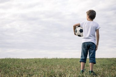 Futbol topuyla sahada duran genç bir çocuğun portresi. Spor anlayışı.