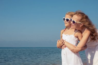 Anne ve kızı o gün plajda dikiliyordu. İnsanlar dışarıda eğleniyordu. Yaz tatili ve arkadaş canlısı aile kavramı.