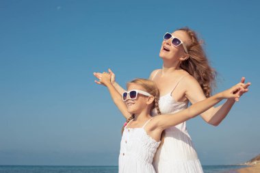 Anne ve kızı o gün plajda dikiliyordu. İnsanlar dışarıda eğleniyordu. Yaz tatili ve arkadaş canlısı aile kavramı.