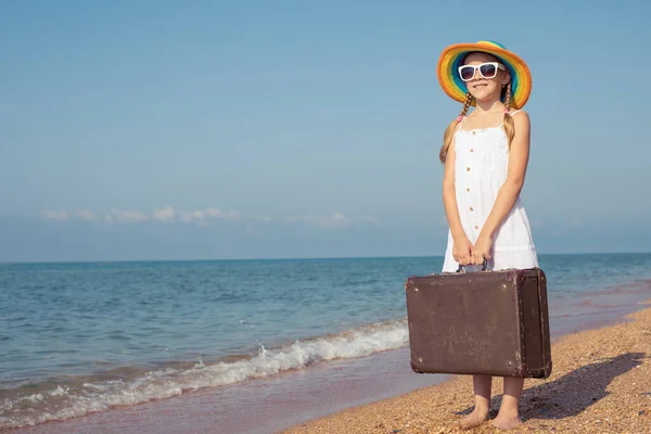 ビーチにスーツケースを着た幸せな女の子が一人います 子供は屋外で楽しんでいる 夏休みの概念 — ストック写真