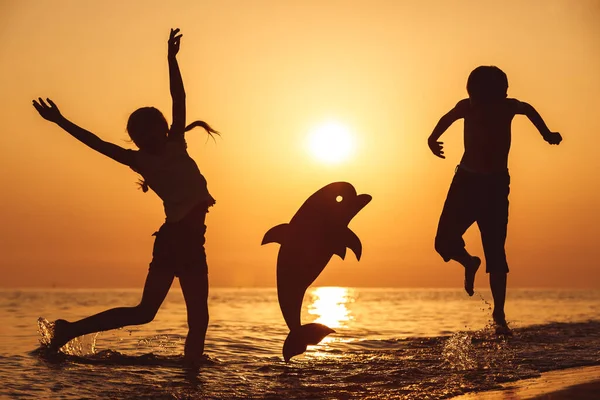 시간에 해변에서 뛰어오르는 판지로 돌고래와 있습니다 애들은 밖에서 재밌게 놀아요 — 스톡 사진
