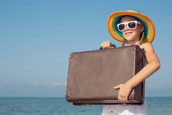 ビーチにスーツケースを着た幸せな女の子が一人います 子供は屋外で楽しんでいる 夏休みの概念 ストックフォト
