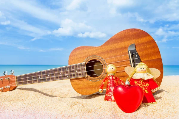 two Christmas doll an angel give a Heart on the sand beach and b