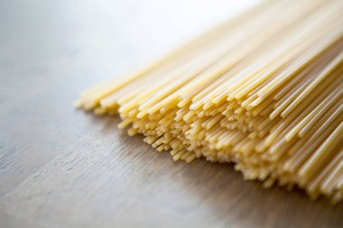 Pişmemiş İtalyan satır spagetti üzerinde ahşap masa, seçici foc