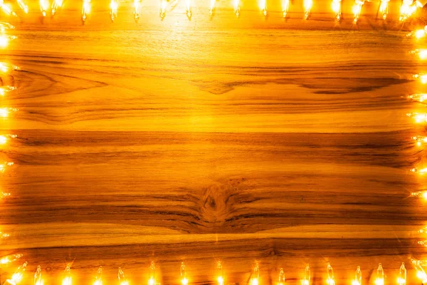 Christmas lights frame on golden wooden background — Stock Photo, Image