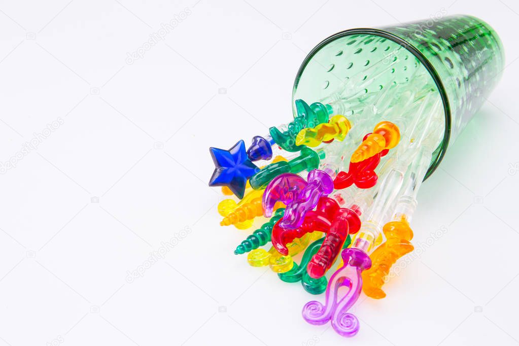 Colorful plastic swizzle sticks spilled from glass on white back