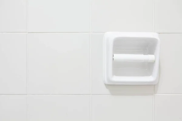 Rolo de papel higiênico vazio montado em uma parede de azulejos — Fotografia de Stock
