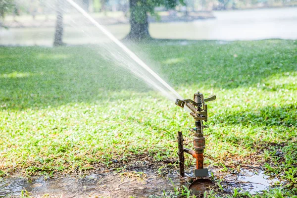 Gartenarbeit Rasensprenger sprüht Wasser über das grüne Gras in der — Stockfoto