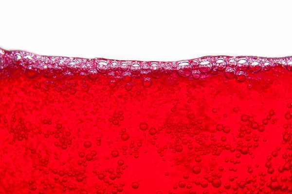 Agua de soda roja salpicando con burbujas de cerca y punto de rocío en — Foto de Stock