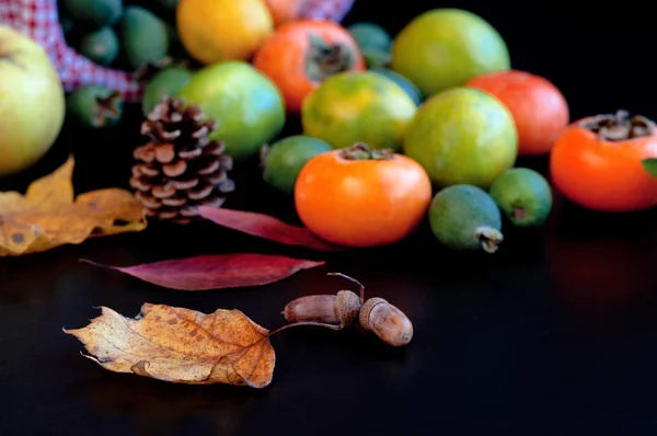 Fruits in basket: persimmons, lemons, pineapple guava with autumn leaves — Stock Photo, Image