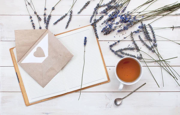 Top view of a cup of tea, lavender, notebook and love letter