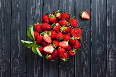 Karanlık bir rustik ahşap arka plan üzerine bir kase taze kırmızı çilek