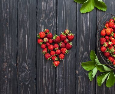 Karanlık bir rustik ahşap arka plan üzerine bir kase taze kırmızı çilek