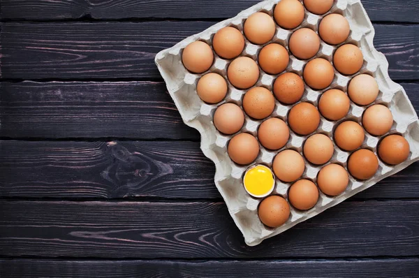 Bir karton kutu içinde tavuk yumurta üstten görünüm kopya alanı bir koyu ahşap tablo.