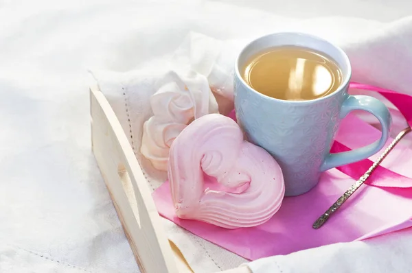 熱いお茶と白い繊維のベッドにハートの形の自家製メレンゲのカップとトレイ 朝のベッドで朝食愛を飲むハーブティー ホット — ストック写真