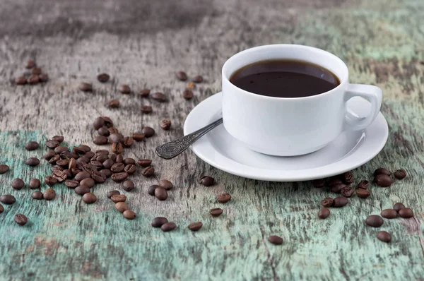 Dağınık tahıl ve gazete ile ahşap bir masa üzerinde siyah kahve bir fincan. Siyah kahve sıcak içecek tahıl gazete ahşap arka plan beyaz fincan Kahvaltı