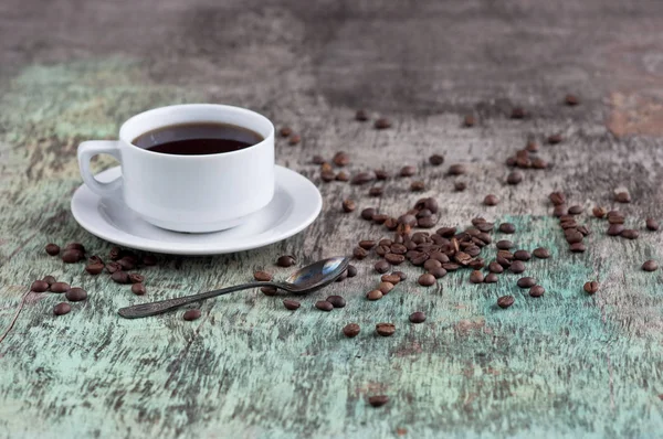 Dağınık tahıl ve gazete ile ahşap bir masa üzerinde siyah kahve bir fincan. Siyah kahve sıcak içecek tahıl gazete ahşap arka plan beyaz fincan Kahvaltı