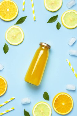 Düz kompozisyon, cam meyve suyu şişeleri ya da taze, taze limon ve portakal dilimleri, yeşil yapraklar, buz küpleri mavi arkaplan manzaralı fotokopi alanı. Citrus meyve suyu konsepti, C vitamini, meyveler.
