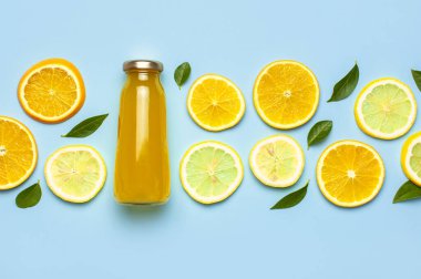 Düz kompozisyon, cam meyve suyu şişeleri ya da taze, taze limon ve portakal dilimleri, yeşil yapraklar, buz küpleri mavi arkaplan manzaralı fotokopi alanı. Citrus meyve suyu konsepti, C vitamini, meyveler.