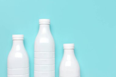 Mavi turkuaz arka plan manzaralı süt ürünleri için beyaz plastik şişe kapları düz yerde yatıyordu. Plastik Kefir Yoğurt Şişe Sütü. Paketleme şablonu modeli. Tasarımınız için düzenName