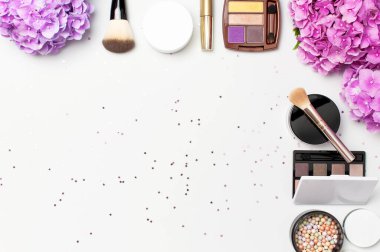 Dekoratif kozmetik maskara tozu ruj göz farı allık makyaj fırçası pembe ortanca çiçekler ışık arka plan üst görünümü Düz konfeti yıldız konfeti seti. Güzellik blogger kavramı. Moda arka plan