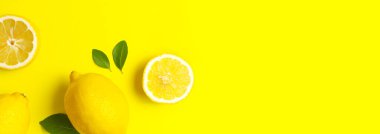 Taze limonlar ve parlak sarı arka planda yeşil yapraklarla yaratıcı bir altyapı. Üst görünüm düz kopya alanı. Limonlu turunçgiller minimum C vitamini bileşimi, limon dilimleriyle.