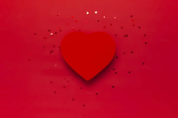 Czerwone pudełko w kształcie serca i konfetti na czerwonym tle widok góry Flat lay. Kreatywna kompozycja na Walentynki, koncepcja miłości, prezent urodzinowy, Dzień Matki, tło świąteczne — Zdjęcie stockowe