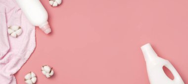 Beyaz plastik deterjan ambalajı, sıvı toz, çamaşır deterjanı, havlular ve pembe arka planda pamuk çiçekleri. Düz görünüm kopyalama alanı yatıyordu. Biyolojik organik ürün. Çevre temizleme kavramı