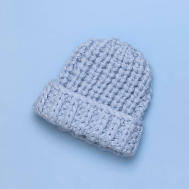 Mavi arka plan manzaralı kadınlar için düz mavi örülü kış şapkası. Havalı yün şapka, soğuk için kış aksesuarları konsepti. Reklam, alışveriş, kış indirimi.