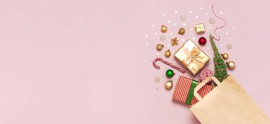 Yeni yıl Noel kompozisyonu. Kağıt torba ve Noel süslemeleri altın hediyeler Noel topları konfeti dalları konfetileri pembe zemin üzerinde Şeker Çubuğu düz görüş alanı üzerinde yatıyordu Kış 2020 Xmas