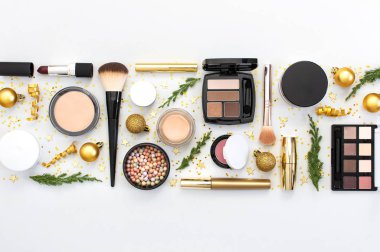 Makyaj maskarası vakfı krem ruj göz farı göz farı, yeni yıl süslemeleri altın noel topları konfeti yıldızları düz zemin üzerinde köknar dalları. Kozmetik, Noel Xmas