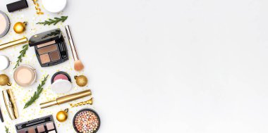 Makyaj maskarası vakfı krem ruj göz farı göz farı, yeni yıl süslemeleri altın noel topları konfeti yıldızları düz zemin üzerinde köknar dalları. Kozmetik, Noel Xmas