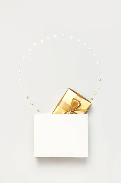 Bellissimo regalo d'oro bianco sacchetto di carta coriandoli stelle su sfondo grigio vista dall'alto Flat lay. Capodanno presenta decorazioni festive 2020 celebrazione. Buon Natale Buone Feste card — Foto Stock