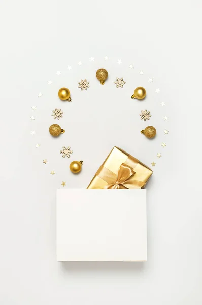 Schöne goldene Geschenk weiße Papiertüte Konfetti Sterne Weihnachtskugeln auf grauem Hintergrund Ansicht flach lag. Das neue Jahr präsentiert festliche Dekorationen. Frohe Weihnachten frohe Feiertage Karte — Stockfoto
