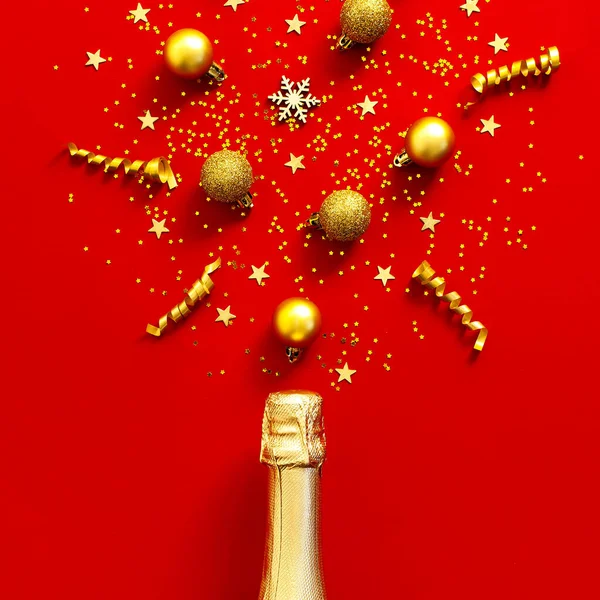 Noel ve Yeni Yıl geçmişi. Şampanya şişesi, altın noel baloları, şenlikli kurdeleler, köknar dalları, kırmızı arka planda yıldız konfetileri. Tatil kartı. Festival dekorasyonları 2020 — Stok fotoğraf
