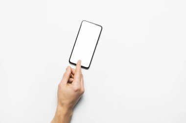 Erkek eller açık gri arka planda beyaz beyaz ekranlı modern bir siyah akıllı telefon tutuyor. Modern teknoloji, telefon, cihazlar, dokunmatik ekran, tasarımınız için şablon. Model
